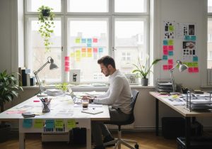 Ein kreativer Profi arbeitet am Laptop und strukturiert Kundenfeedback mit digitalen Tools in einem hellen modernen Büro.