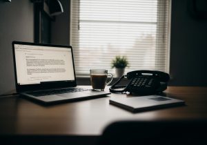 Ein Experte sitzt nachts konzentriert vor dem Laptop mit Telefon und Kaffee, bereit für einen dringenden Auftrag.